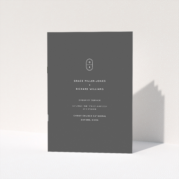 "Midnight Monogram wedding order of service booklet featuring sleek modern design with bold monochromatic colour scheme and personalised monogram emblem.". This is a view of the front