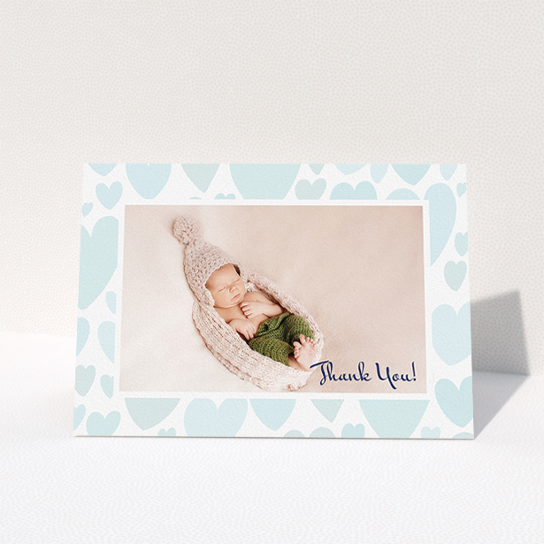 A new baby thank you card design titled "Pastel Hearts". It is an A5 card in a landscape orientation. It is a photographic new baby thank you card with room for 1 photo. "Pastel Hearts" is available as a folded card, with tones of blue and white.