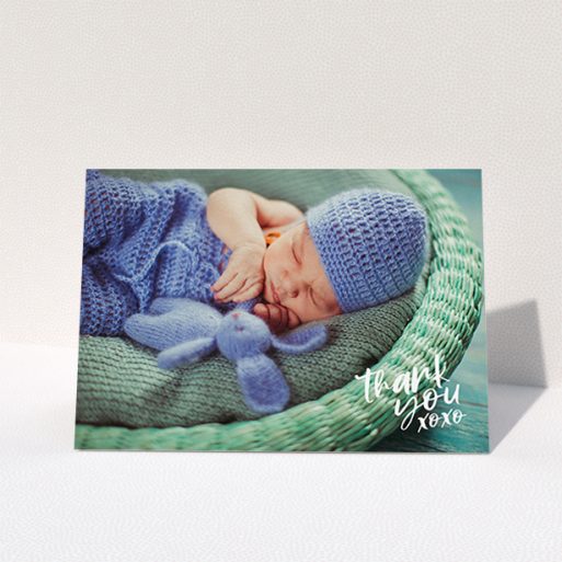 A new baby thank you card template titled "Thanks In the Corner". It is an A6 card in a landscape orientation. It is a photographic new baby thank you card with room for 1 photo. "Thanks In the Corner" is available as a folded card, with mainly white colouring.