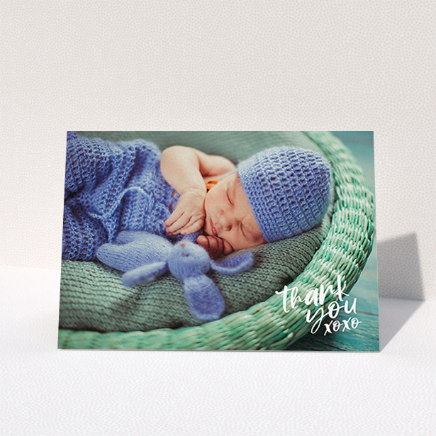 A new baby thank you card template titled "Thanks In the Corner". It is an A6 card in a landscape orientation. It is a photographic new baby thank you card with room for 1 photo. "Thanks In the Corner" is available as a folded card, with mainly white colouring.