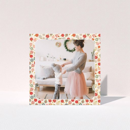 A personalised christmas card called "Bauble Photo". It is a square (148mm x 148mm) card in a square orientation. It is a photographic personalised christmas card with room for 1 photo. "Bauble Photo" is available as a folded card, with tones of pink, red and light blue.