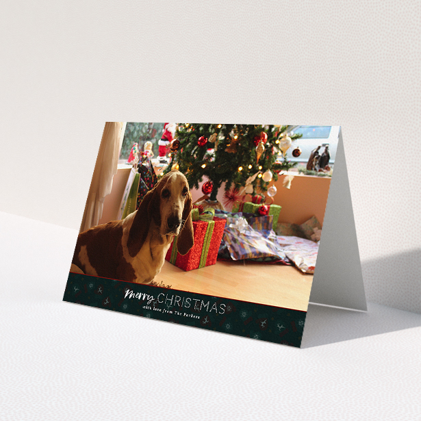 A personalised christmas card named 'Bottom of the Stocking'. It is an A5 card in a landscape orientation. It is a photographic personalised christmas card with room for 1 photo. 'Bottom of the Stocking' is available as a folded card, with tones of dark green and red.