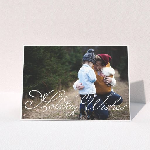 A personalised christmas card called "Holiday Wishes". It is an A5 card in a landscape orientation. It is a photographic personalised christmas card with room for 1 photo. "Holiday Wishes" is available as a folded card, with mainly white colouring.