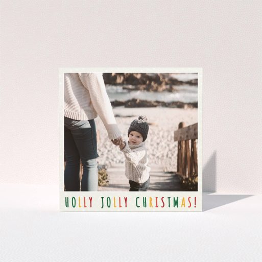 A personalised christmas card design called "Holly, and indeed, Jolly". It is a square (148mm x 148mm) card in a square orientation. It is a photographic personalised christmas card with room for 1 photo. "Holly, and indeed, Jolly" is available as a folded card, with tones of light cream and red.