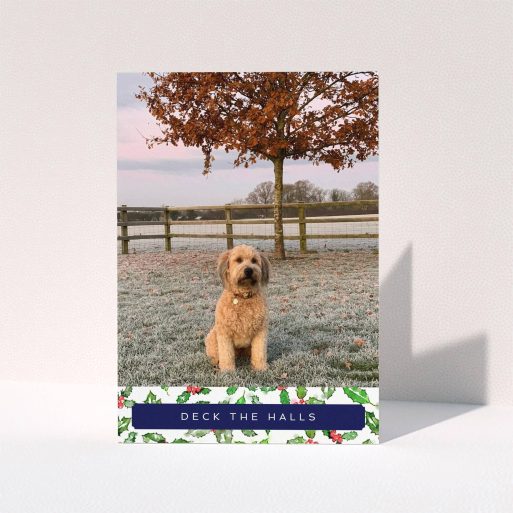 A personalised christmas card design named "Holly Bottom". It is an A5 card in a portrait orientation. It is a photographic personalised christmas card with room for 1 photo. "Holly Bottom" is available as a folded card, with tones of navy blue, red and green.