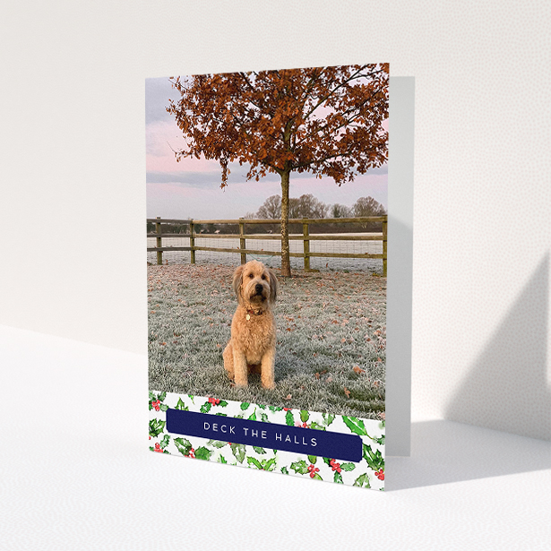 A personalised christmas card design named 'Holly Bottom'. It is an A5 card in a portrait orientation. It is a photographic personalised christmas card with room for 1 photo. 'Holly Bottom' is available as a folded card, with tones of navy blue, red and green.
