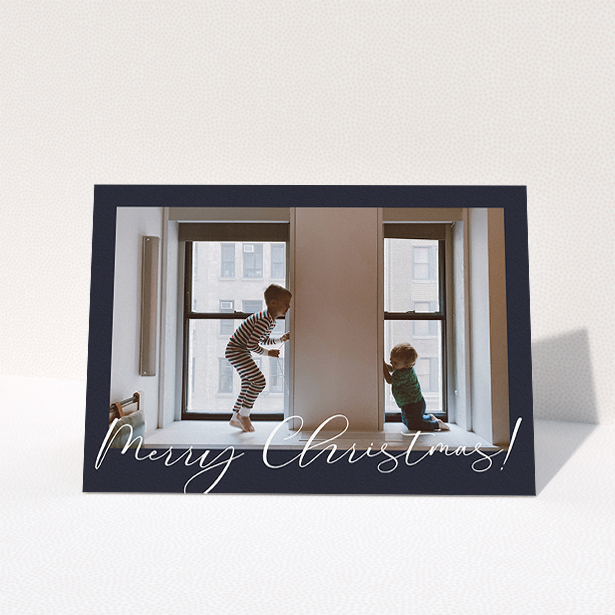 A personalised christmas card template titled "Moody Blue Crimbo". It is an A5 card in a landscape orientation. It is a photographic personalised christmas card with room for 1 photo. "Moody Blue Crimbo" is available as a folded card, with mainly white colouring.