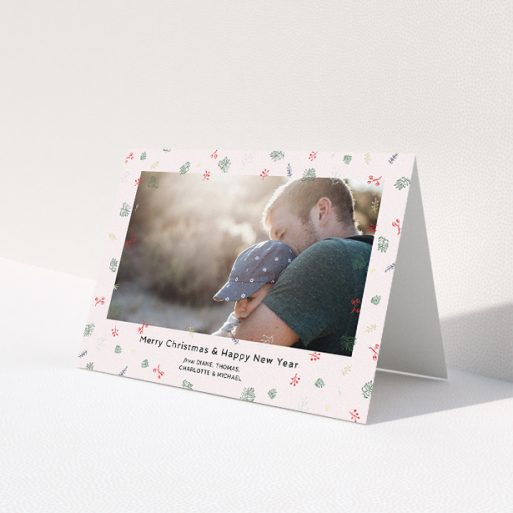 A personalised christmas card design named 'Noeliage'. It is an A5 card in a landscape orientation. It is a photographic personalised christmas card with room for 1 photo. 'Noeliage' is available as a folded card, with tones of light pink, green and light blue.