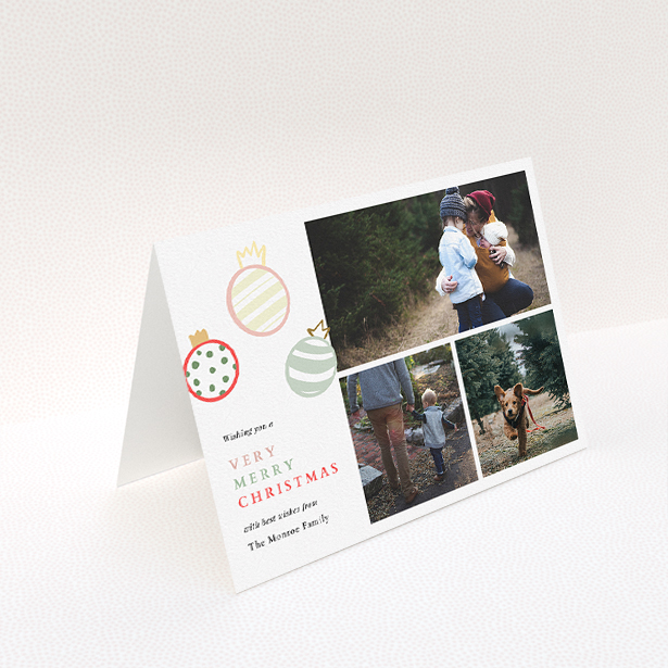 A personalised christmas card named "Pastel Baubles". It is an A5 card in a landscape orientation. It is a photographic personalised christmas card with room for 3 photos. "Pastel Baubles" is available as a folded card, with tones of white and green.