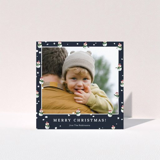 A personalised christmas card template titled "Snowmen and Snow". It is a square (148mm x 148mm) card in a square orientation. It is a photographic personalised christmas card with room for 1 photo. "Snowmen and Snow" is available as a folded card, with tones of navy blue, red and white.