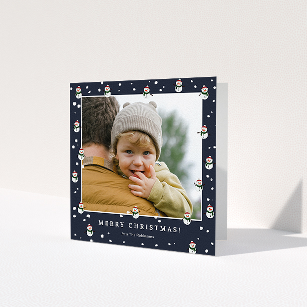 A personalised christmas card template titled 'Snowmen and Snow'. It is a square (148mm x 148mm) card in a square orientation. It is a photographic personalised christmas card with room for 1 photo. 'Snowmen and Snow' is available as a folded card, with tones of navy blue, red and white.