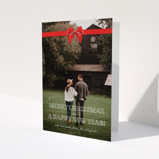 A personalised christmas card called 'Under the Tree'. It is an A5 card in a portrait orientation. It is a photographic personalised christmas card with room for 1 photo. 'Under the Tree' is available as a folded card, with mainly red colouring.