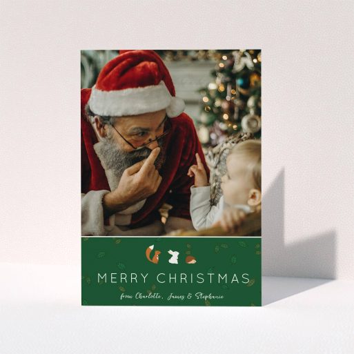 A personalised christmas card design named "Woodland Christmas". It is an A6 card in a portrait orientation. It is a photographic personalised christmas card with room for 1 photo. "Woodland Christmas" is available as a folded card, with tones of green and white.