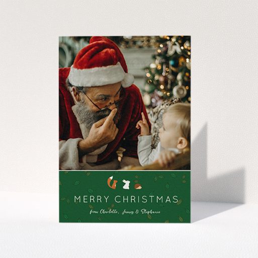 A personalised christmas card design named "Woodland Christmas". It is an A6 card in a portrait orientation. It is a photographic personalised christmas card with room for 1 photo. "Woodland Christmas" is available as a folded card, with tones of green and white.