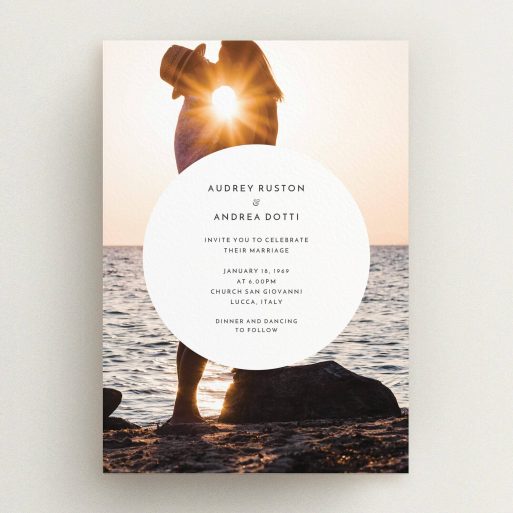A personalised wedding invite design titled "Surrounded". It is an A5 invite in a portrait orientation. It is a photographic personalised wedding invite with room for 1 photo. "Surrounded" is available as a flat invite, with mainly white colouring.