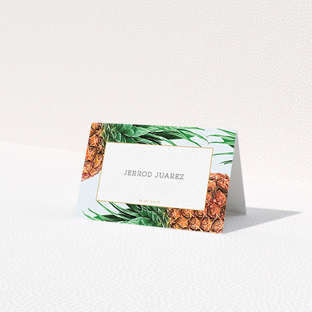 A place setting card called 'Pineapples falling'. It is an 85 x 55mm card in a landscape orientation. 'Pineapples falling' is available as a folded card, with tones of green, green and brown.