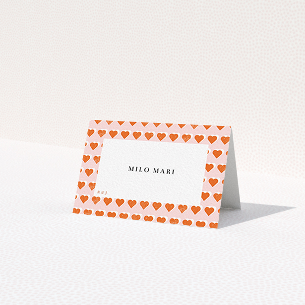 A place setting card design named "Rustic Hearts". It is an 85 x 55mm card in a landscape orientation. "Rustic Hearts" is available as a folded card, with tones of pink and orange.