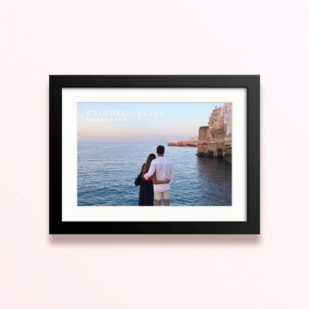 Framed and mounted photo print of a couple by the sea with cliffs in the background and text overlay.