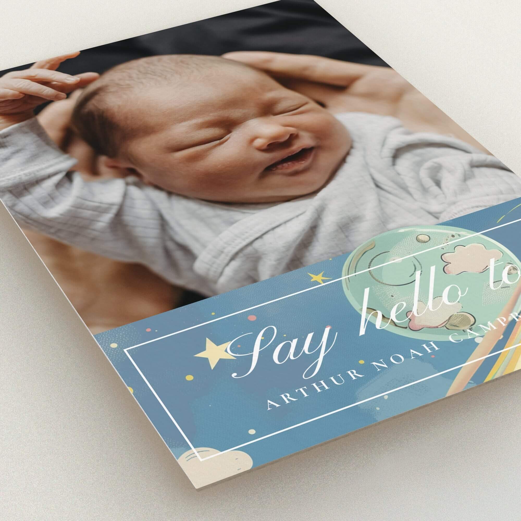 Birth announcement card with one photo of a newborn in arms and decorative celestial design