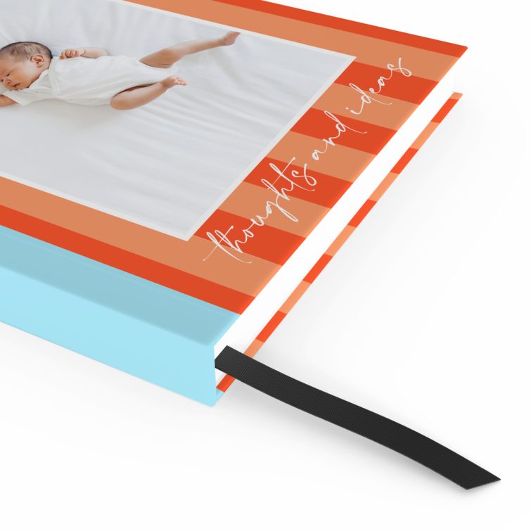 Portrait orientation notebook design with orange and blue striped cover and one photo of a baby.