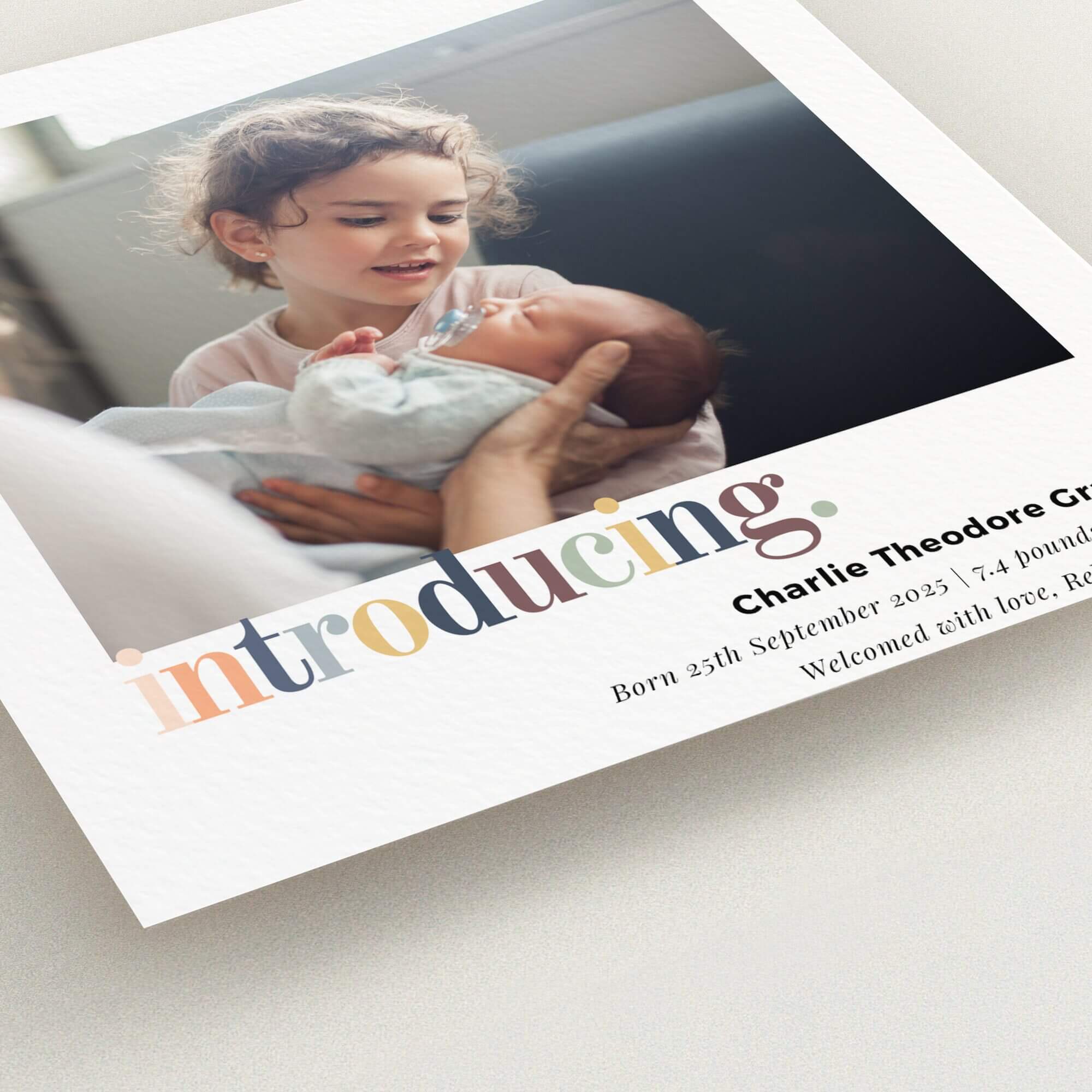 Colourful and modern birth announcement card design featuring one photo of a child meeting a newborn.