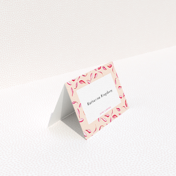 A table place card design named "Petal avalanche". It is an 85 x 55mm card in a landscape orientation. "Petal avalanche" is available as a folded card, with tones of pink, red and white.