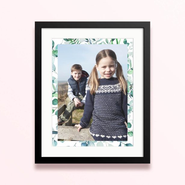 Framed and mounted photo print with two children in nature with a leaf border design.