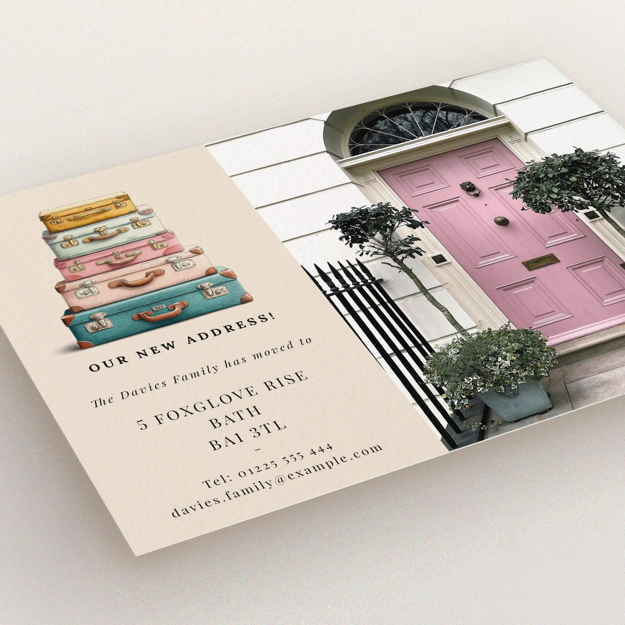 Colourful change of address card design featuring stacked suitcases illustration and a pink front door image.