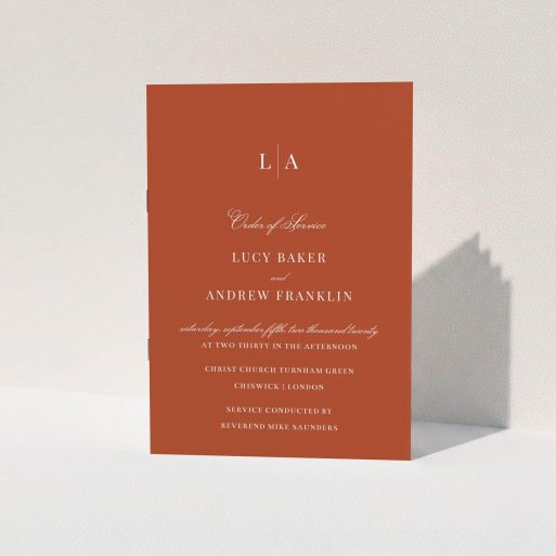 A wedding order of service named "Dark Ochre Monogrammed". It is an A5 booklet in a portrait orientation. "Dark Ochre Monogrammed" is available as a folded booklet booklet, with mainly dark orange colouring.