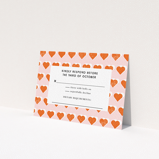 A wedding response card called 'Rustic Hearts'. It is an A7 card in a landscape orientation. 'Rustic Hearts' is available as a flat card, with tones of pink and orange.