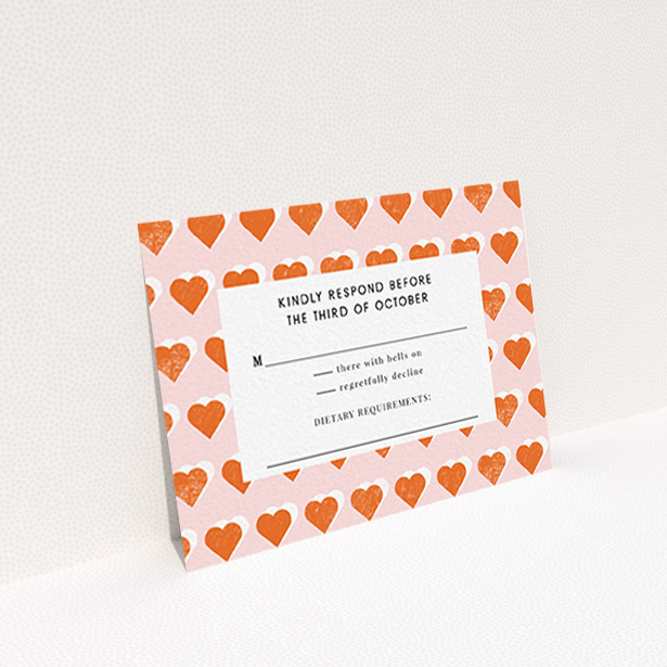 A wedding response card called "Rustic Hearts". It is an A7 card in a landscape orientation. "Rustic Hearts" is available as a flat card, with tones of pink and orange.