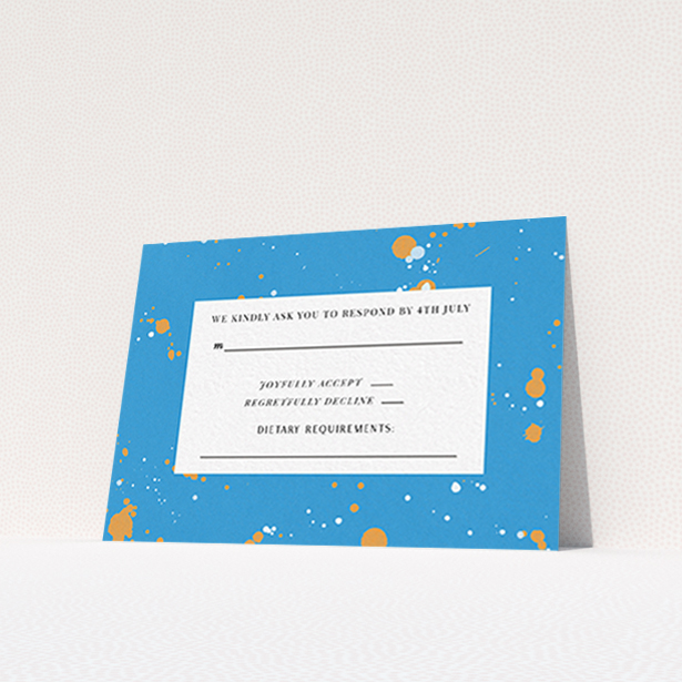 A wedding rsvp card design named "Orange Splatters". It is an A7 card in a landscape orientation. "Orange Splatters" is available as a flat card, with tones of light blue and orange.