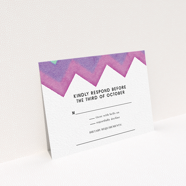 A wedding rsvp card design named "Vibrant Peaks". It is an A7 card in a landscape orientation. "Vibrant Peaks" is available as a flat card, with tones of white, dark pink and purple.