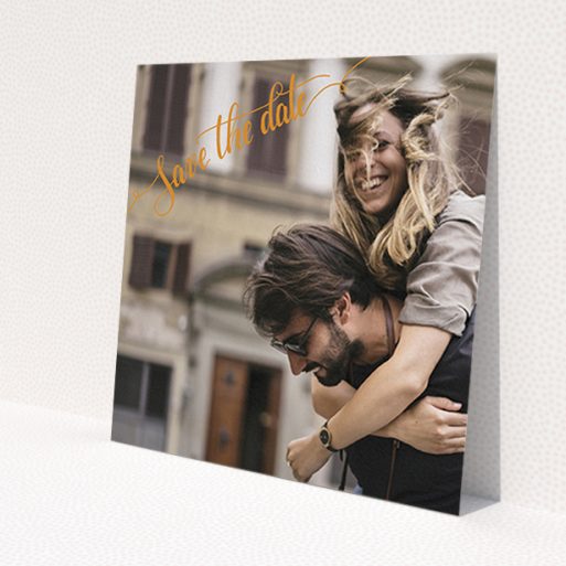 A wedding save the date card named 'Corner Typography Photo'. It is a square (148mm x 148mm) card in a square orientation. It is a photographic wedding save the date card with room for 1 photo. 'Corner Typography Photo' is available as a flat card, with mainly light orange colouring.