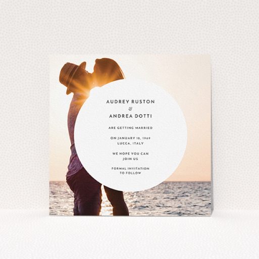 A wedding save the date card design called "Surrounded". It is a square (148mm x 148mm) card in a square orientation. It is a photographic wedding save the date card with room for 1 photo. "Surrounded" is available as a flat card, with mainly white colouring.