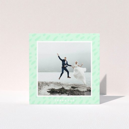 A wedding thank you card design named "A symphony in green". It is a square (148mm x 148mm) card in a square orientation. It is a photographic wedding thank you card with room for 1 photo. "A symphony in green" is available as a folded card, with tones of green and white.