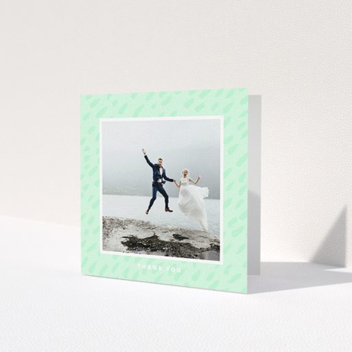 A wedding thank you card design named 'A symphony in green'. It is a square (148mm x 148mm) card in a square orientation. It is a photographic wedding thank you card with room for 1 photo. 'A symphony in green' is available as a folded card, with tones of green and white.
