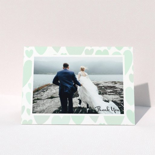 A wedding thank you card design named "Mint Heart Frame". It is an A6 card in a landscape orientation. It is a photographic wedding thank you card with room for 1 photo. "Mint Heart Frame" is available as a folded card, with tones of green and white.