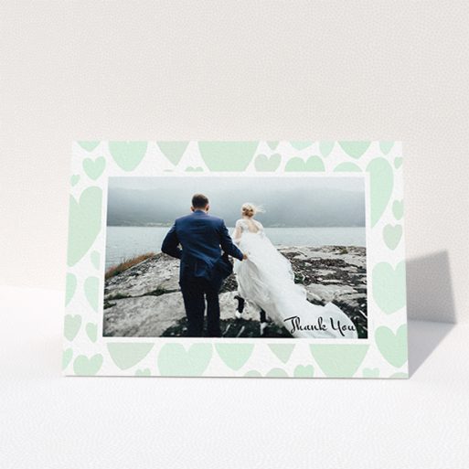 A wedding thank you card design named "Mint Heart Frame". It is an A6 card in a landscape orientation. It is a photographic wedding thank you card with room for 1 photo. "Mint Heart Frame" is available as a folded card, with tones of green and white.