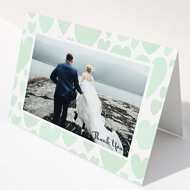 A wedding thank you card design named "Mint Heart Frame". It is an A6 card in a landscape orientation. It is a photographic wedding thank you card with room for 1 photo. "Mint Heart Frame" is available as a folded card, with tones of green and white.