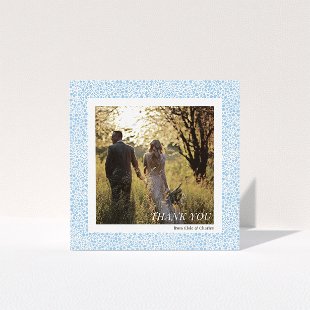 A wedding thank you card design called "Surrounded by flowers". It is a square (148mm x 148mm) card in a square orientation. It is a photographic wedding thank you card with room for 1 photo. "Surrounded by flowers" is available as a folded card, with tones of blue and white.