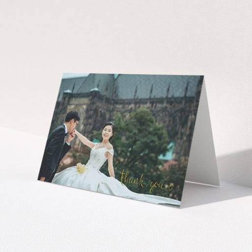 A wedding thank you card design titled 'Thank you with a heart'. It is an A5 card in a landscape orientation. It is a photographic wedding thank you card with room for 1 photo. 'Thank you with a heart' is available as a folded card, with mainly gold colouring.