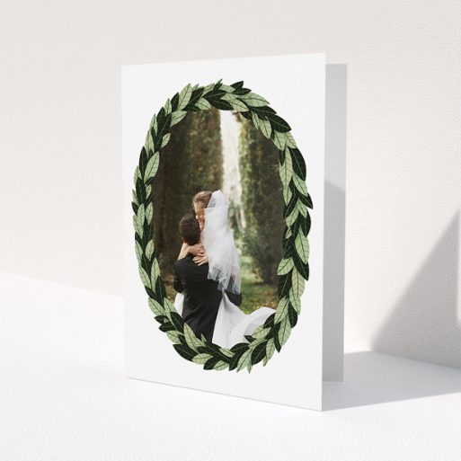 A wedding thank you card design titled 'Thick Wreath Frame'. It is an A5 card in a portrait orientation. It is a photographic wedding thank you card with room for 1 photo. 'Thick Wreath Frame' is available as a folded card, with tones of light green and dark green.