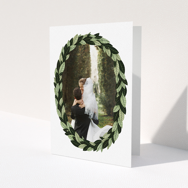 A wedding thank you card design titled 'Thick Wreath Frame'. It is an A5 card in a portrait orientation. It is a photographic wedding thank you card with room for 1 photo. 'Thick Wreath Frame' is available as a folded card, with tones of light green and dark green.