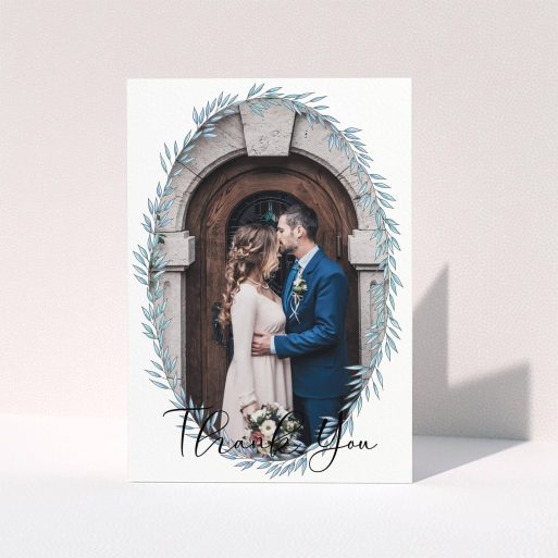 A wedding thank you card design named "Tussled Wreath Frame". It is an A6 card in a portrait orientation. It is a photographic wedding thank you card with room for 1 photo. "Tussled Wreath Frame" is available as a folded card, with mainly blue colouring.