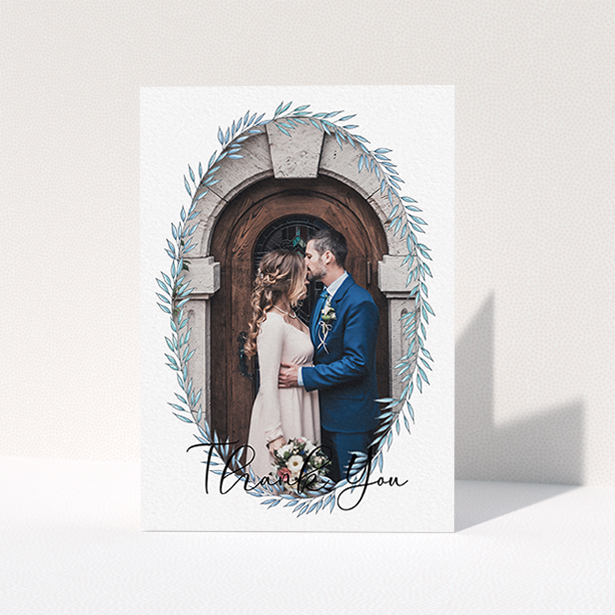 A wedding thank you card design named "Tussled Wreath Frame". It is an A6 card in a portrait orientation. It is a photographic wedding thank you card with room for 1 photo. "Tussled Wreath Frame" is available as a folded card, with mainly blue colouring.