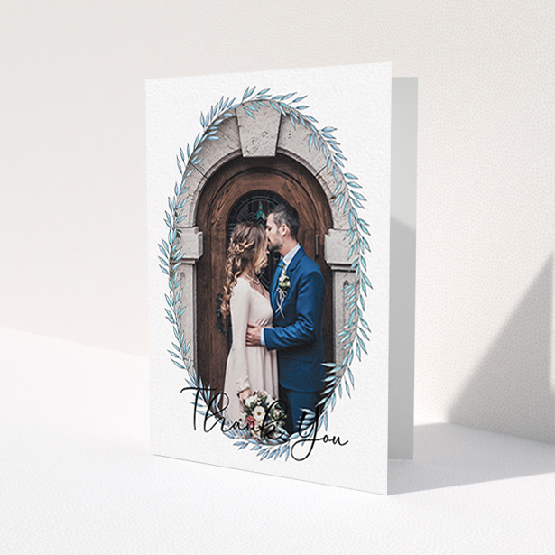 A wedding thank you card design named "Tussled Wreath Frame". It is an A6 card in a portrait orientation. It is a photographic wedding thank you card with room for 1 photo. "Tussled Wreath Frame" is available as a folded card, with mainly blue colouring.
